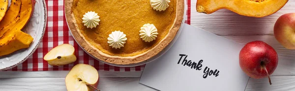 Top view of pumpkin pie, ripe apples and thank you card on wooden white table, panoramic shot — Stock Photo