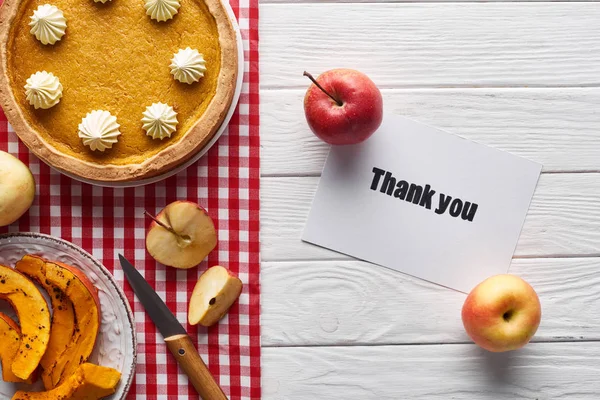 Top view of pumpkin pie, ripe apples and thank you card on wooden white table — Stock Photo