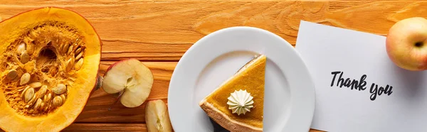 Vue du dessus de tarte à la citrouille, pommes mûres et carte de remerciement sur table en bois, vue panoramique — Photo de stock