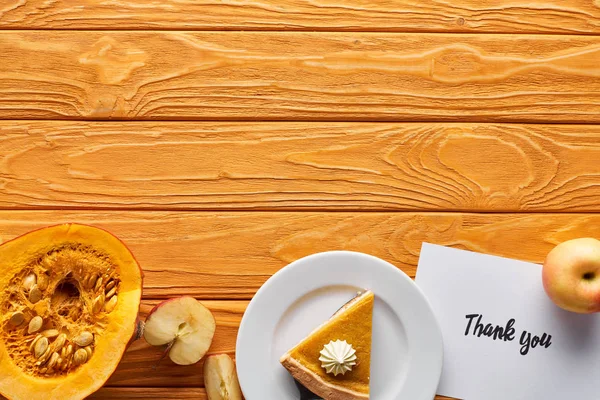 Vista superior de pastel de calabaza, manzanas maduras y tarjeta de agradecimiento en la mesa de madera con espacio para copiar - foto de stock