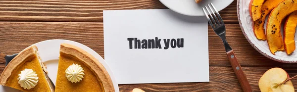 Top view of pumpkin pie, ripe apples and thank you card on wooden brown table, panoramic shot — Stock Photo