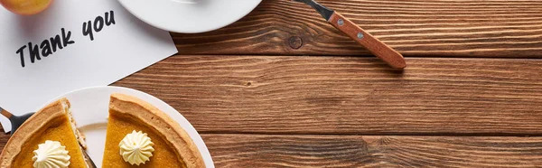 Vue du dessus de tarte à la citrouille et carte de remerciement sur table brune en bois, vue panoramique — Photo de stock