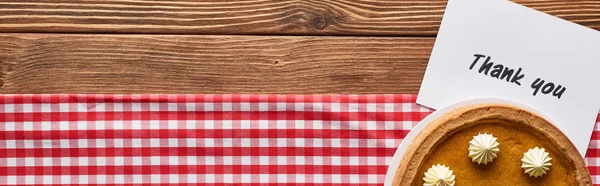 Top view of pumpkin pie and thank you card on wooden brown table with red plaid napkin, panoramic shot — Stock Photo