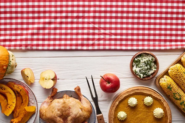 Blick von oben auf Kürbiskuchen, Truthahn und Gemüse, serviert an weißem Holztisch mit karierter Serviette zum Erntedankdinner — Stockfoto