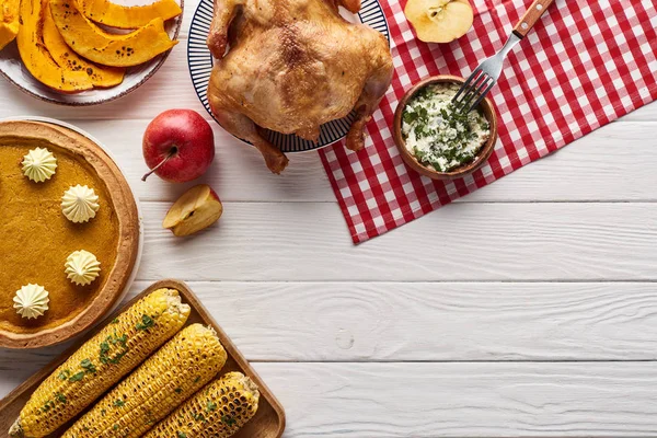 Vista superior del pastel de calabaza, pavo y verduras servidas en la mesa de madera blanca para la cena de Acción de Gracias - foto de stock