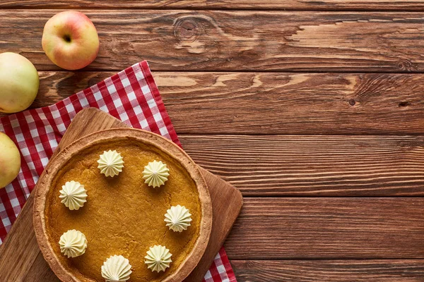 Top view of pumpkin pie and apples served at wooden table with plaid napkin for Thanksgiving dinner — Stock Photo