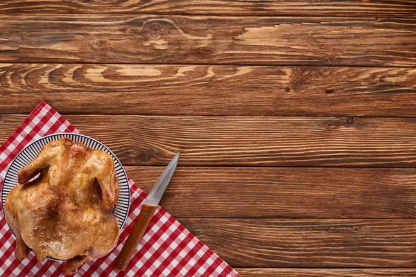 Vista superior del pavo asado con cuchillo en servilleta a cuadros en la mesa de madera para la cena de Acción de Gracias - foto de stock