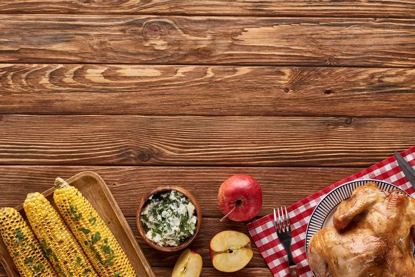 Вид зверху смаженої індички та кукурудзи на грилі, що подається на червоній картатій серветці за дерев'яним столом для вечері на День подяки — стокове фото