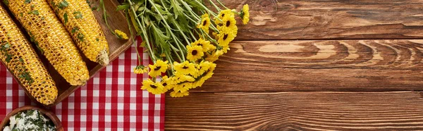 Vista dall'alto del mais grigliato servito vicino a fiori gialli al tavolo di legno per la cena del Ringraziamento, colpo panoramico — Foto stock