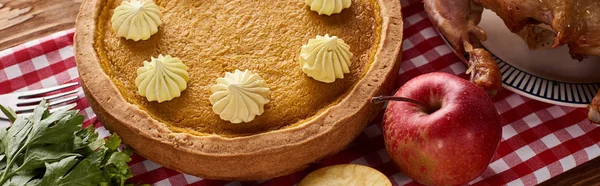 Pastel de calabaza, pavo asado y manzanas en servilleta a cuadros rojo en la mesa de madera para la cena de Acción de Gracias, tiro panorámico - foto de stock