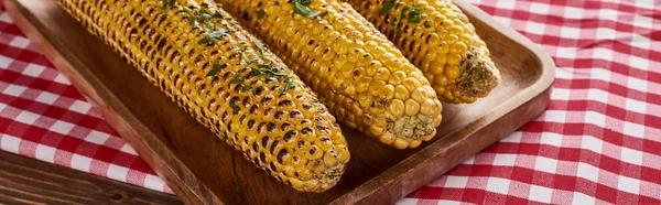 Grilled corn served on red checkered napkin at wooden table for Thanksgiving dinner, panoramic shot — Stock Photo