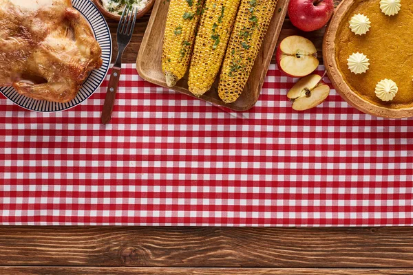 Сверху вид тыквенного пирога, индейки и овощей подается за деревянным столом на ужин в честь Дня благодарения — стоковое фото