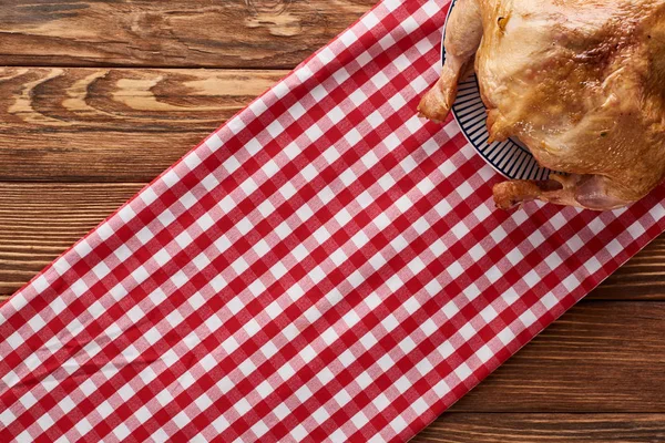 Vue du dessus de la dinde rôtie servie sur une serviette à carreaux rouges à une table en bois pour le dîner de Thanksgiving — Photo de stock
