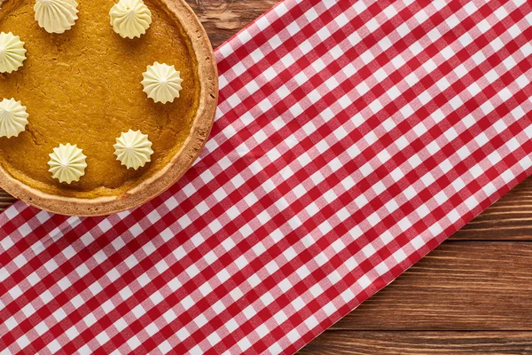 Top view of traditional pumpkin pie on red checkered napkin at wooden table for Thanksgiving dinner — Stock Photo