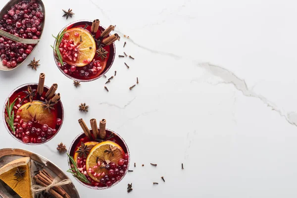 Draufsicht auf Weihnachtscocktails mit Orange, Granatapfel, Zimt, gefrorenen Preiselbeeren und Kuchen — Stockfoto