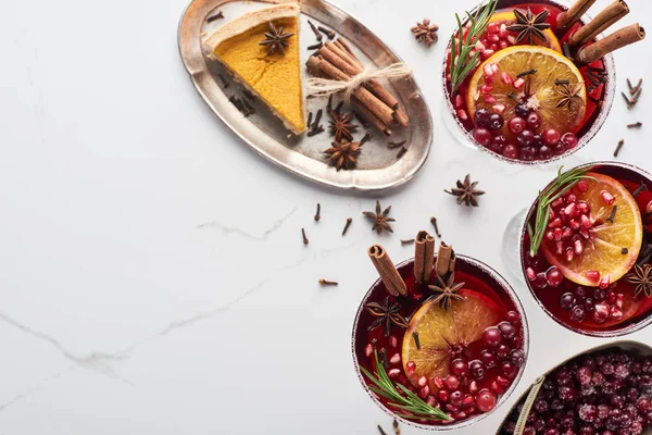 Draufsicht auf Weihnachtscocktails mit Orange, Granatapfel, Zimt, gefrorenen Preiselbeeren und Kuchen — Stockfoto