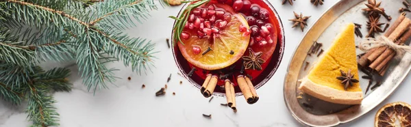 Colpo panoramico di cocktail natalizio con arancia, melograno, cannella e torta su vassoio — Foto stock