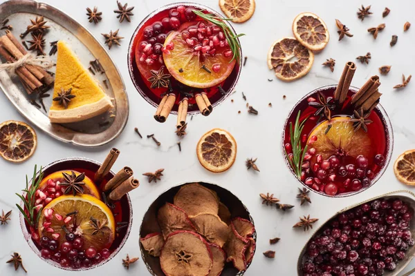 Draufsicht auf Weihnachtscocktails mit Orange, Granatapfel, Zimt, Kuchen auf Tablett, trockenen Äpfeln und gefrorenen Preiselbeeren — Stockfoto