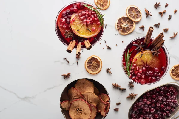 Draufsicht auf Weihnachtscocktails mit Orange, Granatapfel, Zimt, trockenen Äpfeln und gefrorenen Preiselbeeren — Stockfoto