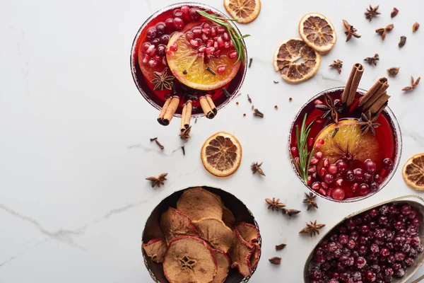 Vue de dessus des cocktails de Noël avec orange, grenade, cannelle, pommes sèches et canneberge congelée — Photo de stock