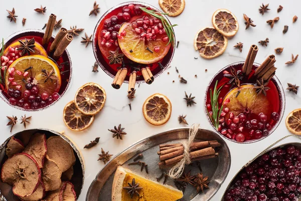 Draufsicht auf Weihnachtscocktails mit Orange, Granatapfel, Zimt, Kuchen auf Tablett, trockenen Äpfeln und gefrorenen Preiselbeeren — Stockfoto