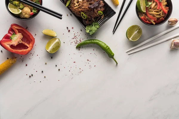 Vista dall'alto di deliziosi tagliatelle thai piccanti vicino bacchette e ingredienti sulla superficie grigio marmo — Foto stock