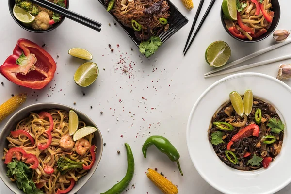 Vista dall'alto di deliziosi tagliatelle thai piccanti vicino bacchette e ingredienti sulla superficie grigio marmo — Foto stock