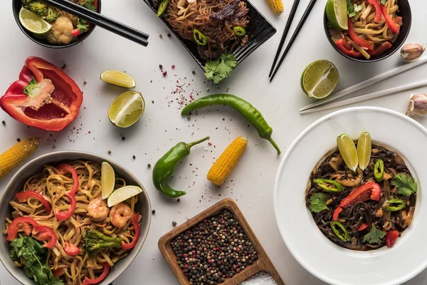 Vista dall'alto di deliziosi tagliatelle thai piccanti vicino bacchette e ingredienti sulla superficie grigio marmo — Foto stock