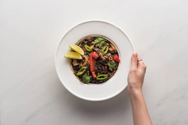 Vista recortada de la mujer sosteniendo plato con deliciosos fideos tailandeses picantes - foto de stock