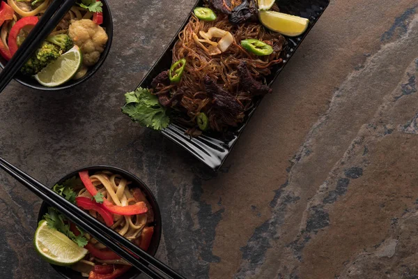 Vista dall'alto di deliziosi tagliatelle thai piccanti con bacchette sulla superficie di pietra — Foto stock