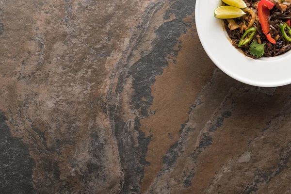 Vue de dessus des nouilles thai épicées savoureuses avec des baguettes sur la surface de la pierre — Photo de stock