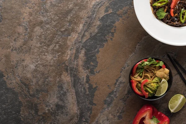 Vue de dessus des nouilles thai épicées savoureuses avec des baguettes sur la surface de la pierre — Photo de stock