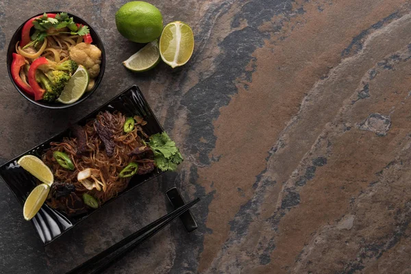 Vue de dessus des nouilles thai épicées savoureuses avec des baguettes sur la surface de la pierre — Photo de stock