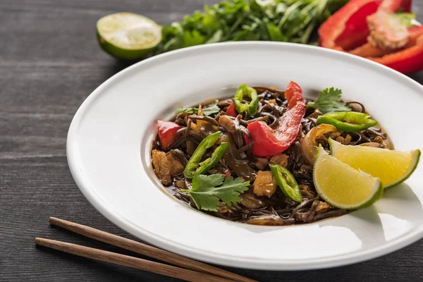 Close up view of delicious spicy thai noodles near chopsticks on wooden grey surface — Stock Photo