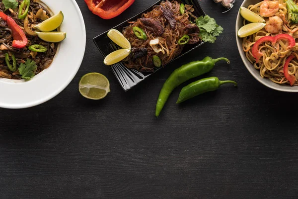 Vista superior de sabrosos fideos tailandeses picantes en la superficie gris de madera - foto de stock