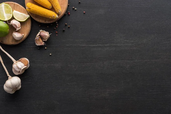 Top view of corn, garlic, peppercorn and lime on wooden grey surface with copy space — Stock Photo