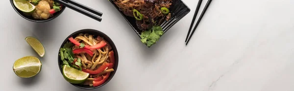Vista superior de deliciosos fideos tailandeses de carne y verduras con palillos en la superficie gris mármol, plano panorámico - foto de stock