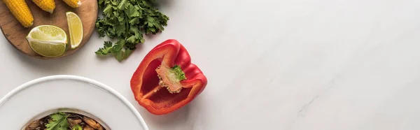 Top view of delicious thai noodles near bell pepper, parsley and corn on marble grey surface, panoramic shot — Stock Photo