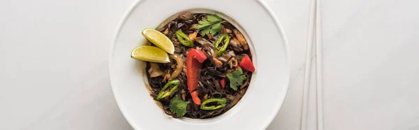 Top view of delicious meat thai noodles with chopsticks on marble grey surface, panoramic shot — Stock Photo