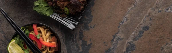 Top view of delicious thai noodles with chopsticks on stone surface, panoramic shot — Stock Photo