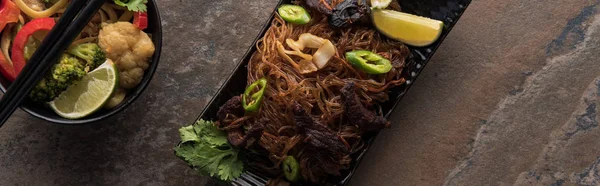 Vista dall'alto di deliziosi spaghetti tailandesi con bacchette sulla superficie in pietra, colpo panoramico — Foto stock