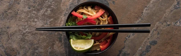 Top view of thai noodles and chopsticks on stone surface, panoramic shot — Stock Photo