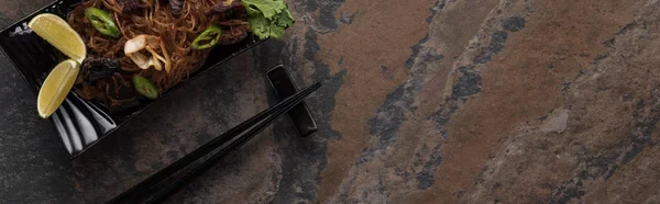 Top view of thai noodles with beef near chopsticks on stone surface, panoramic shot — Stock Photo