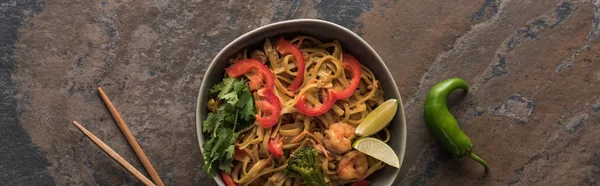 Top view of thai noodles with shrimps near chopsticks and jalapenos, panoramic shot — Stock Photo