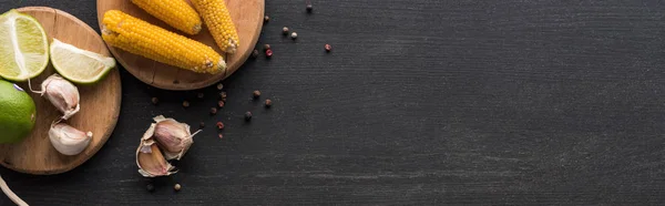 Top view of corn, garlic, peppercorn and lime on wooden grey surface with copy space, panoramic shot — Stock Photo