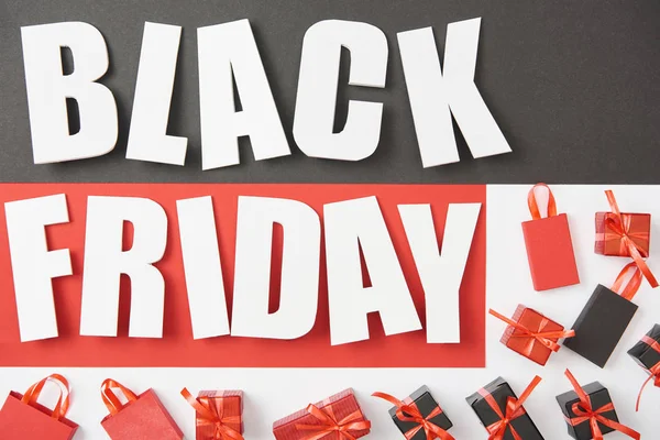 Top view of black friday lettering near presents on black, red and white background — Stock Photo