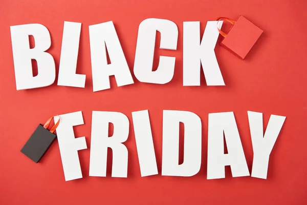 Ansicht von Black Friday White Schriftzug mit Einkaufstaschen auf rotem Hintergrund — Stockfoto