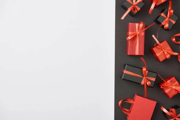 Draufsicht auf dekorative Geschenkboxen und Einkaufstasche auf weißem und schwarzem Hintergrund mit Kopierraum — Stockfoto