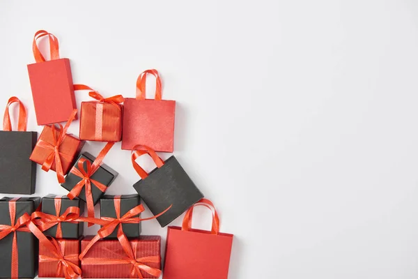 Vista dall'alto di regali neri e rossi e shopping bag su sfondo bianco — Foto stock