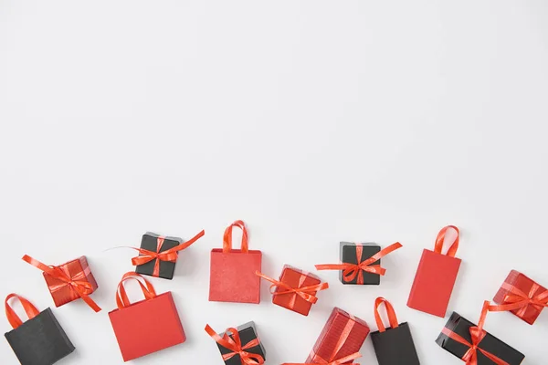 Vista dall'alto di regali neri e rossi e shopping bag su sfondo bianco con spazio copia — Foto stock